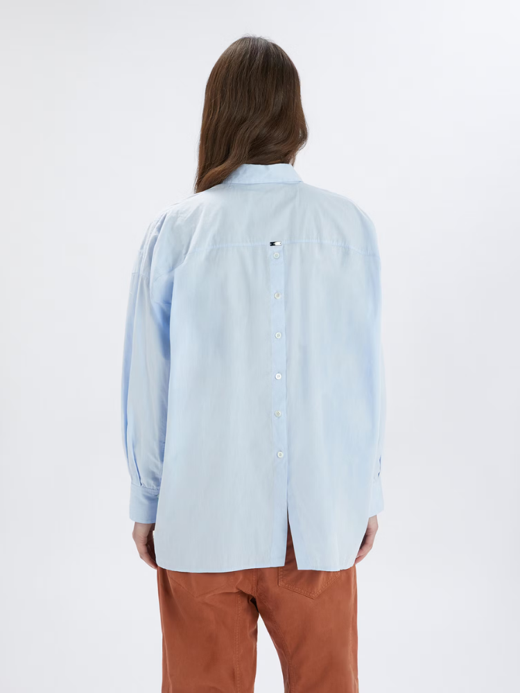 Person wearing a light blue shirt and brown pants on a white background