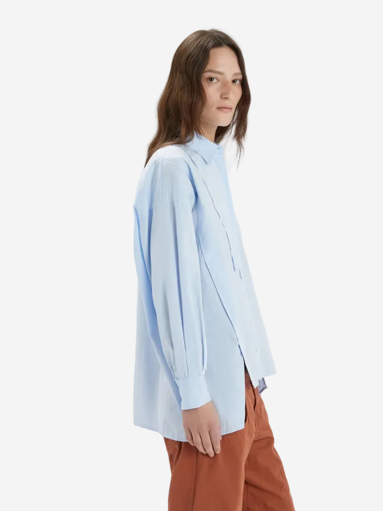 Woman wearing a light blue shirt and brown pants on a white background