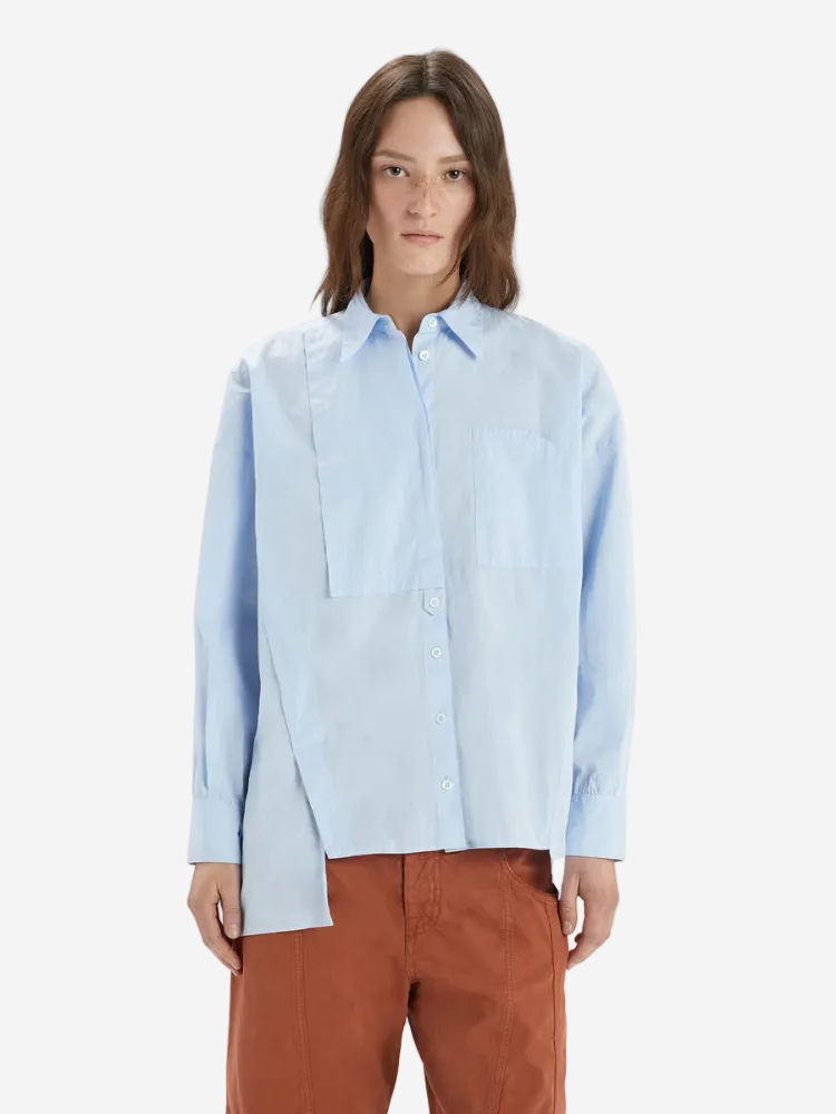 Person wearing a light blue shirt and brown pants on a white background