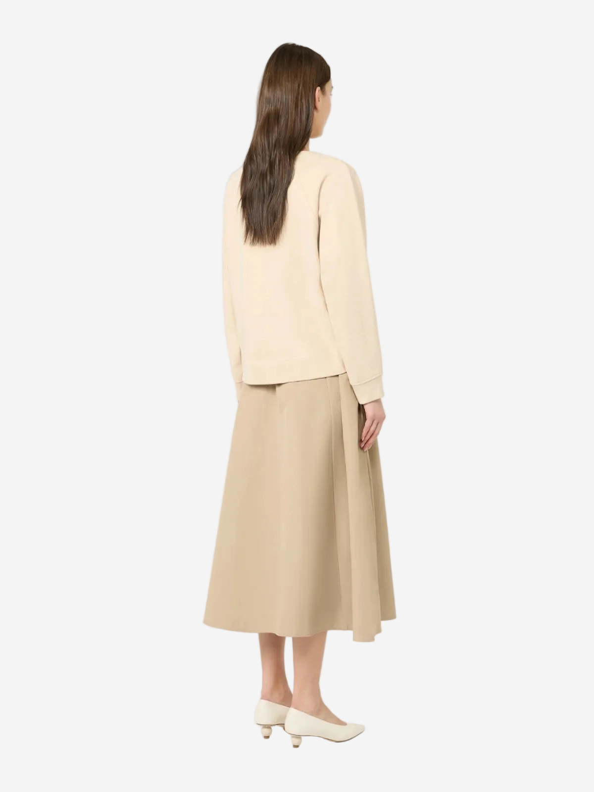 Woman wearing a beige top and beige skirt on a white background