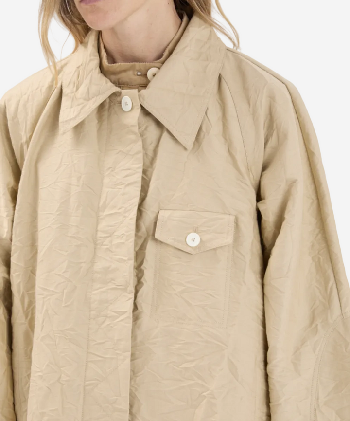 Beige quilted jacket worn by a person on a white background