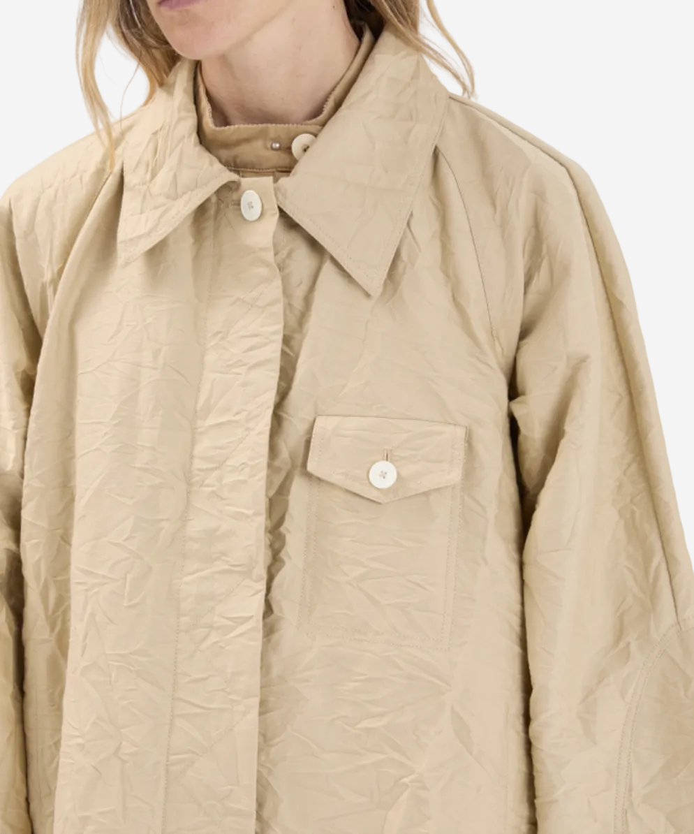 Beige quilted jacket worn by a person on a white background