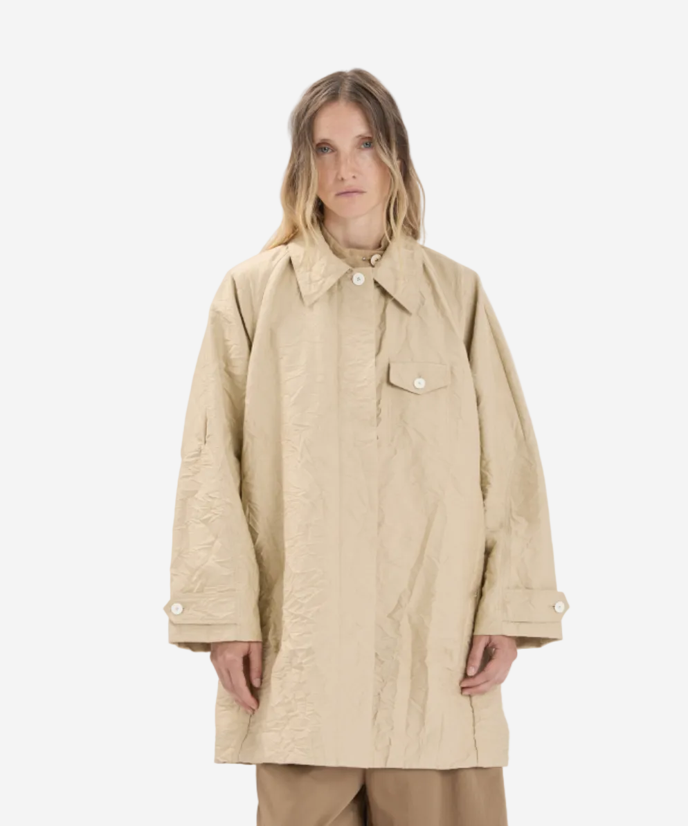 Person wearing a beige coat on a white background