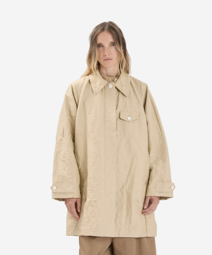 Person wearing a beige coat on a white background