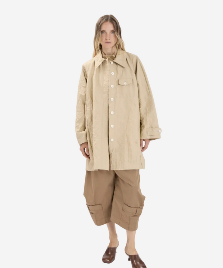 Person wearing a beige coat and pants on a white background