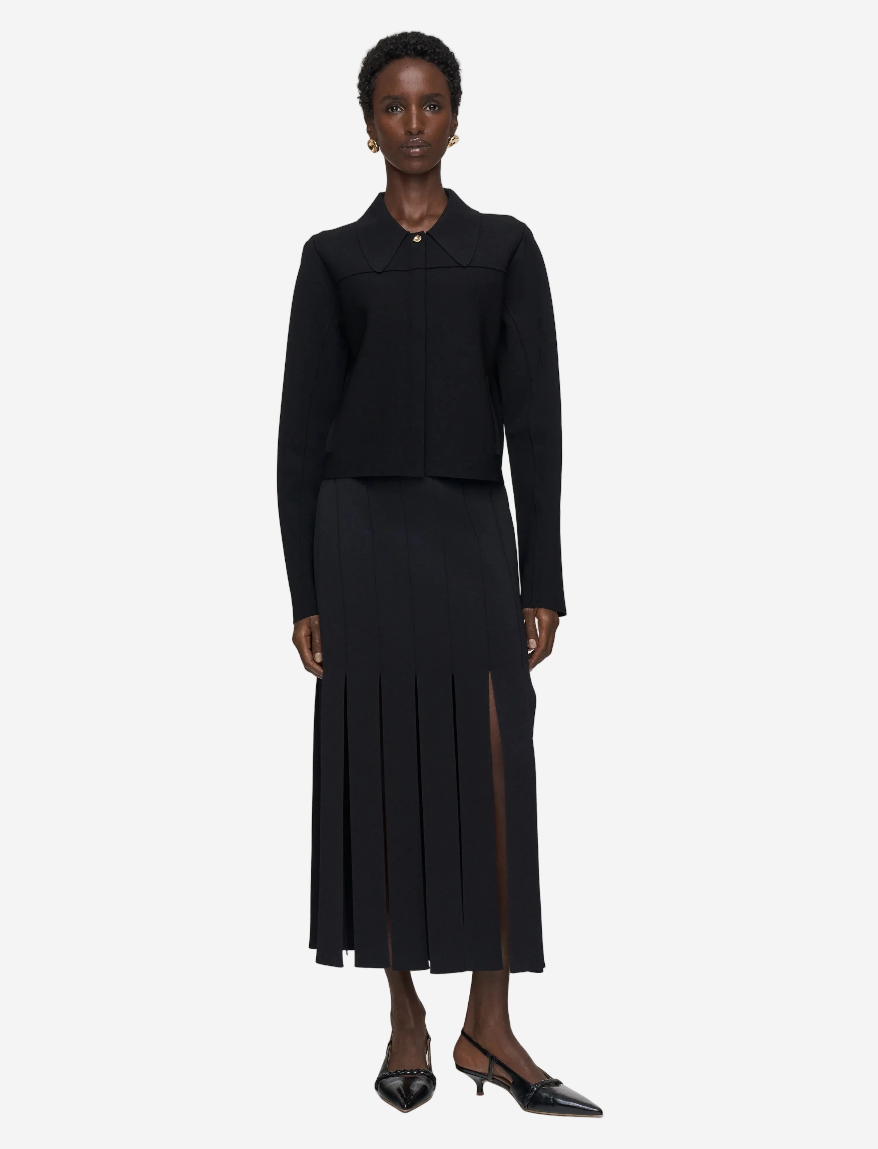 Woman wearing a black outfit with a jacket and skirt on a white background