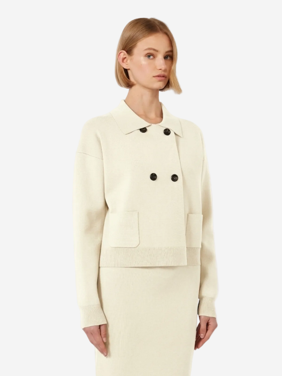 Woman wearing a cream-colored suit with black buttons on a white background