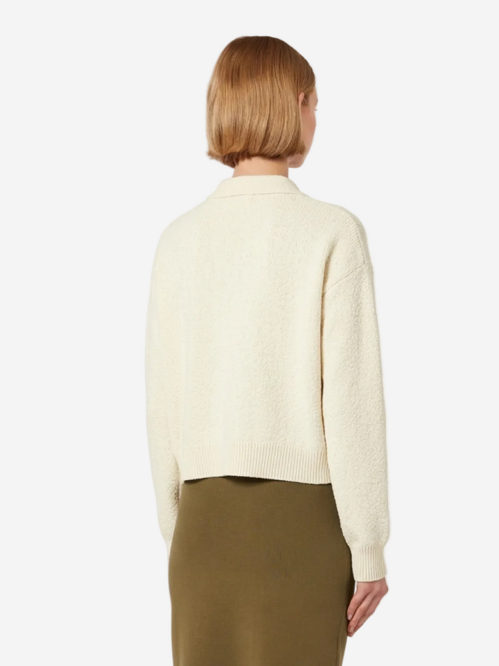 Person wearing a cream sweater and green skirt on a white background