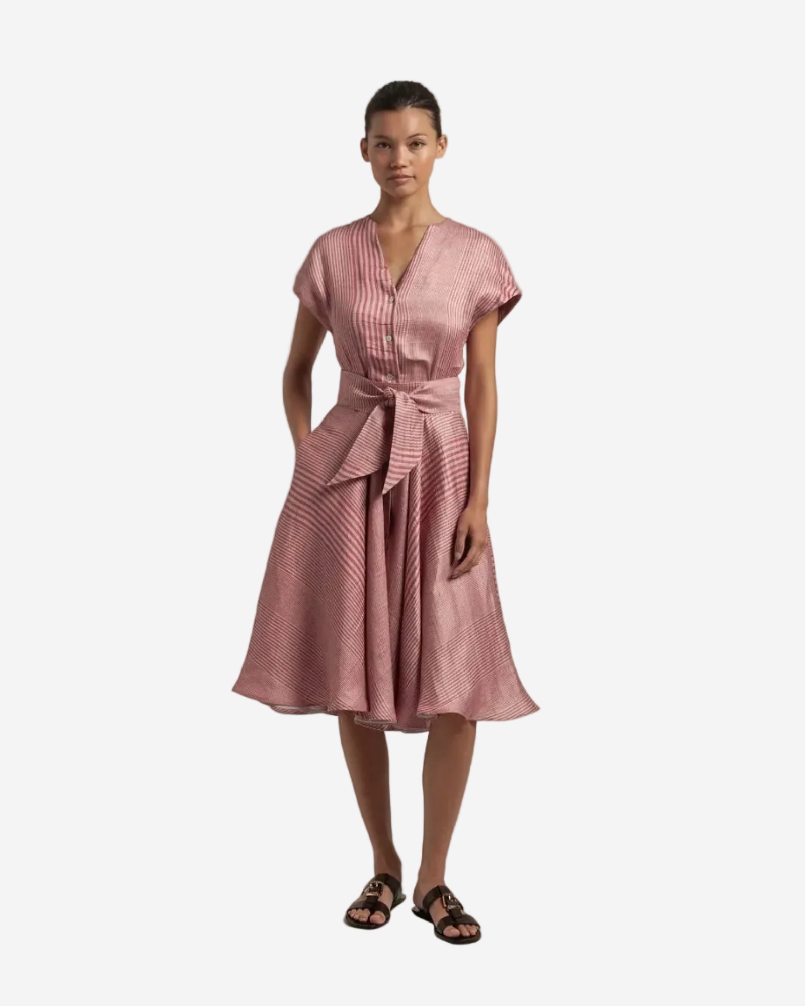 Woman wearing a pink dress with a belt on a plain background