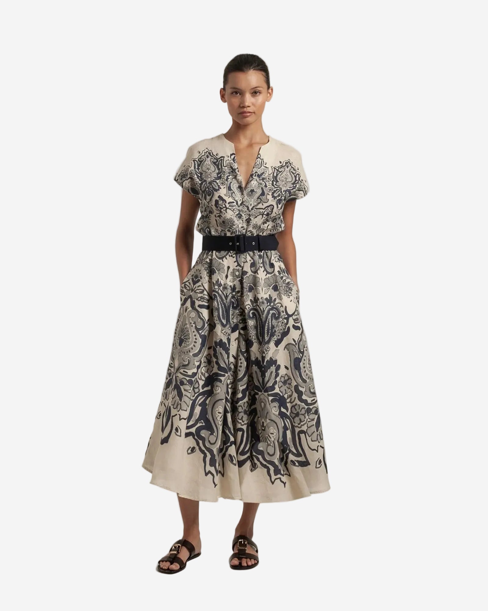Woman wearing a patterned dress with a belt on a plain background