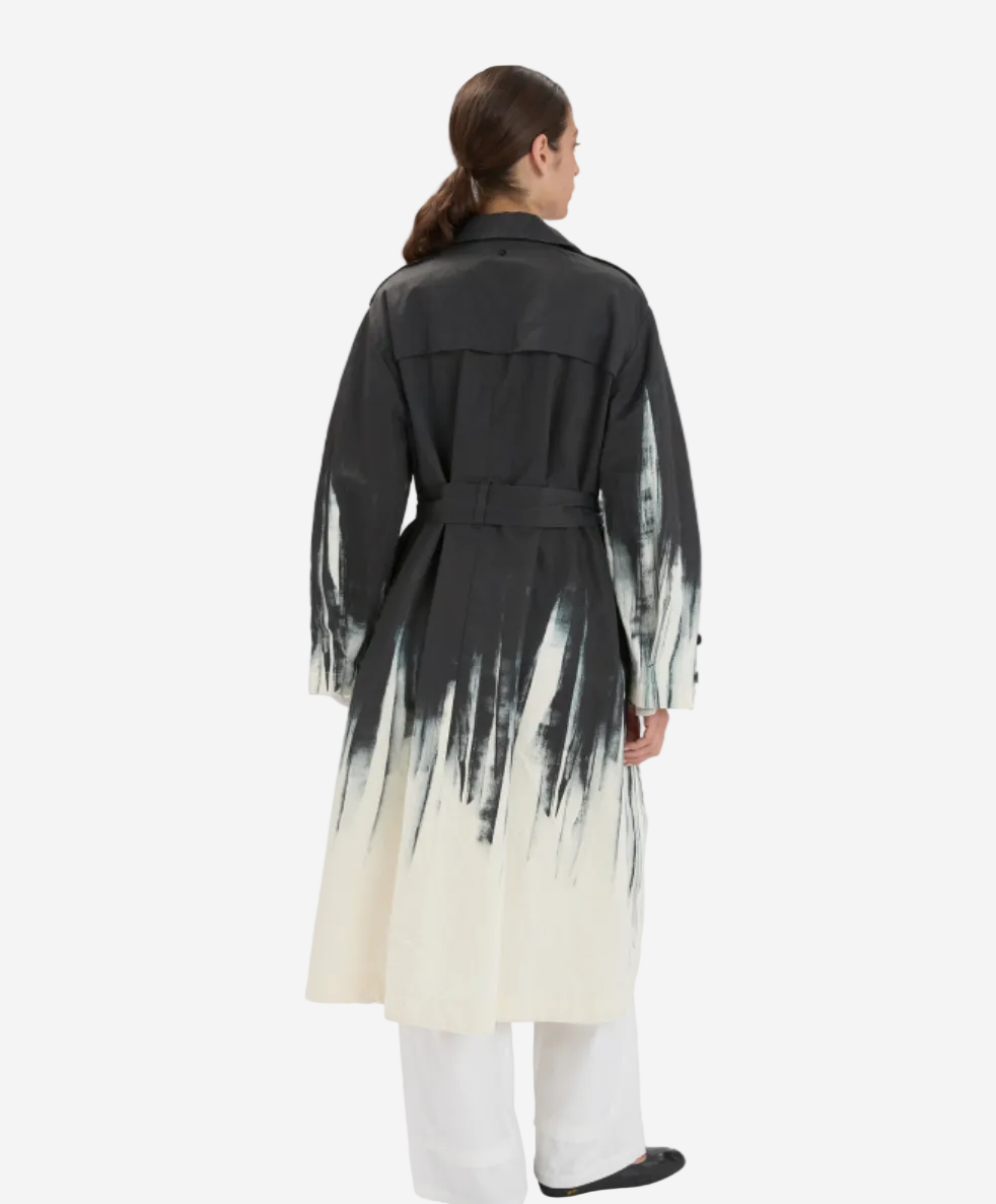 Person wearing a black and white gradient trench coat on a white background