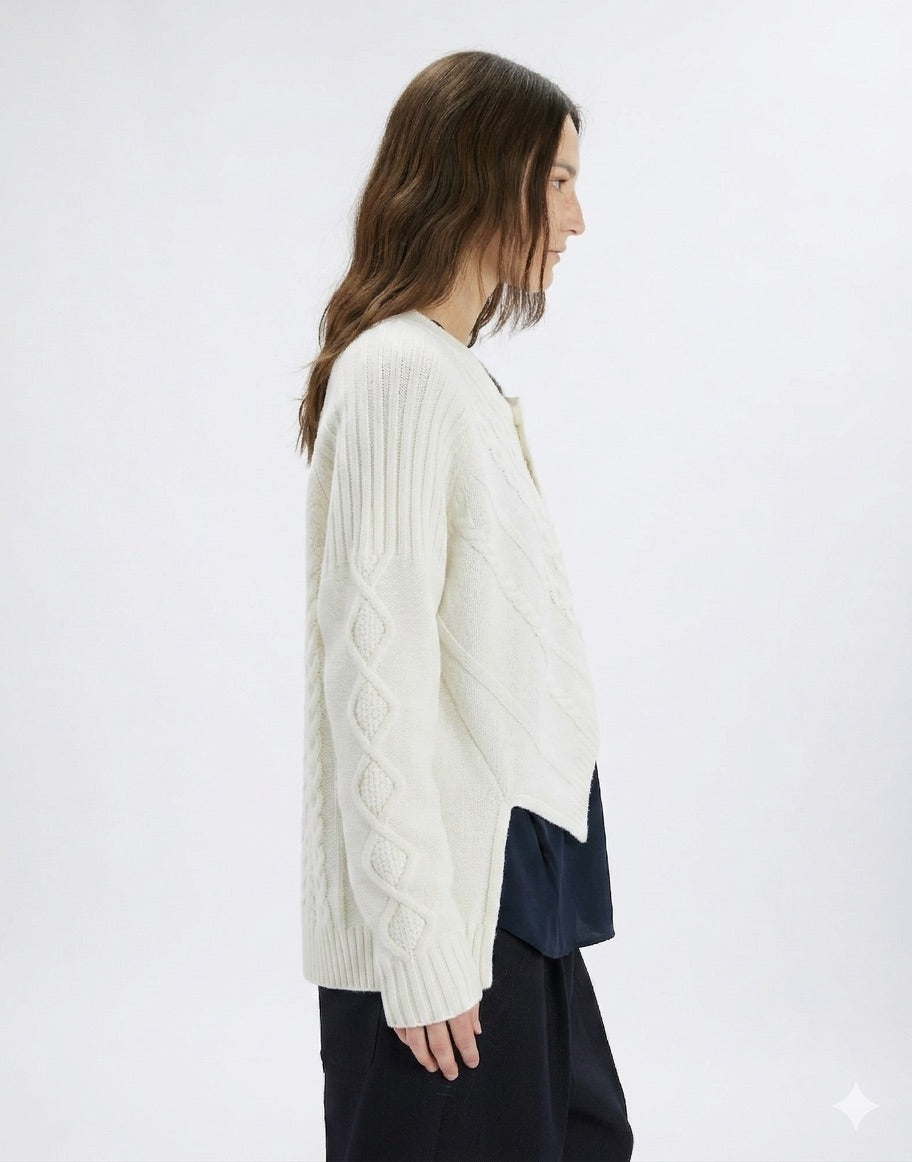 Woman wearing a white cable knit sweater on a white background