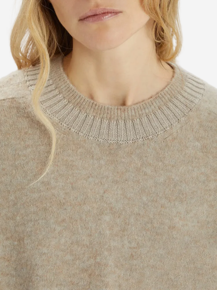 Close-up of a person wearing a beige sweater with a textured neckline.