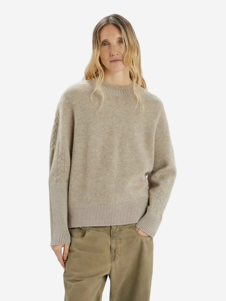 Woman wearing a beige sweater and green pants on a white background