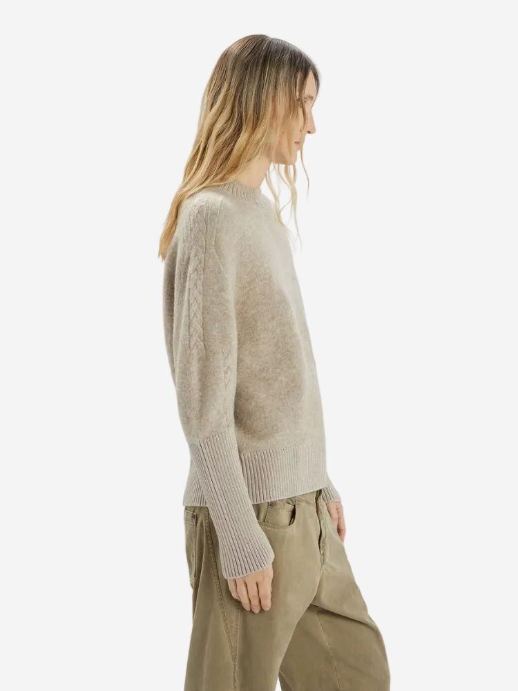 Woman wearing a beige sweater and pants on a white background