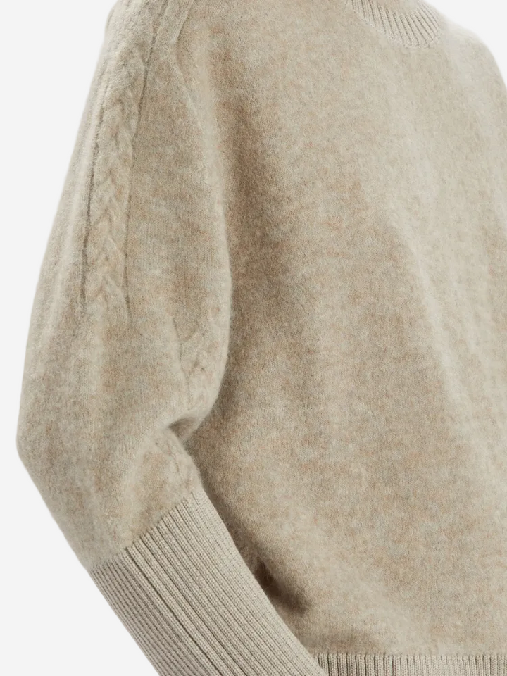 Close-up of a beige sweater with a plain background