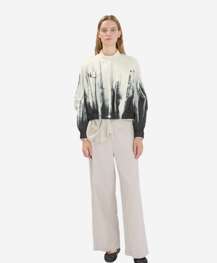 Woman wearing a tie-dye shirt and beige pants on a white background