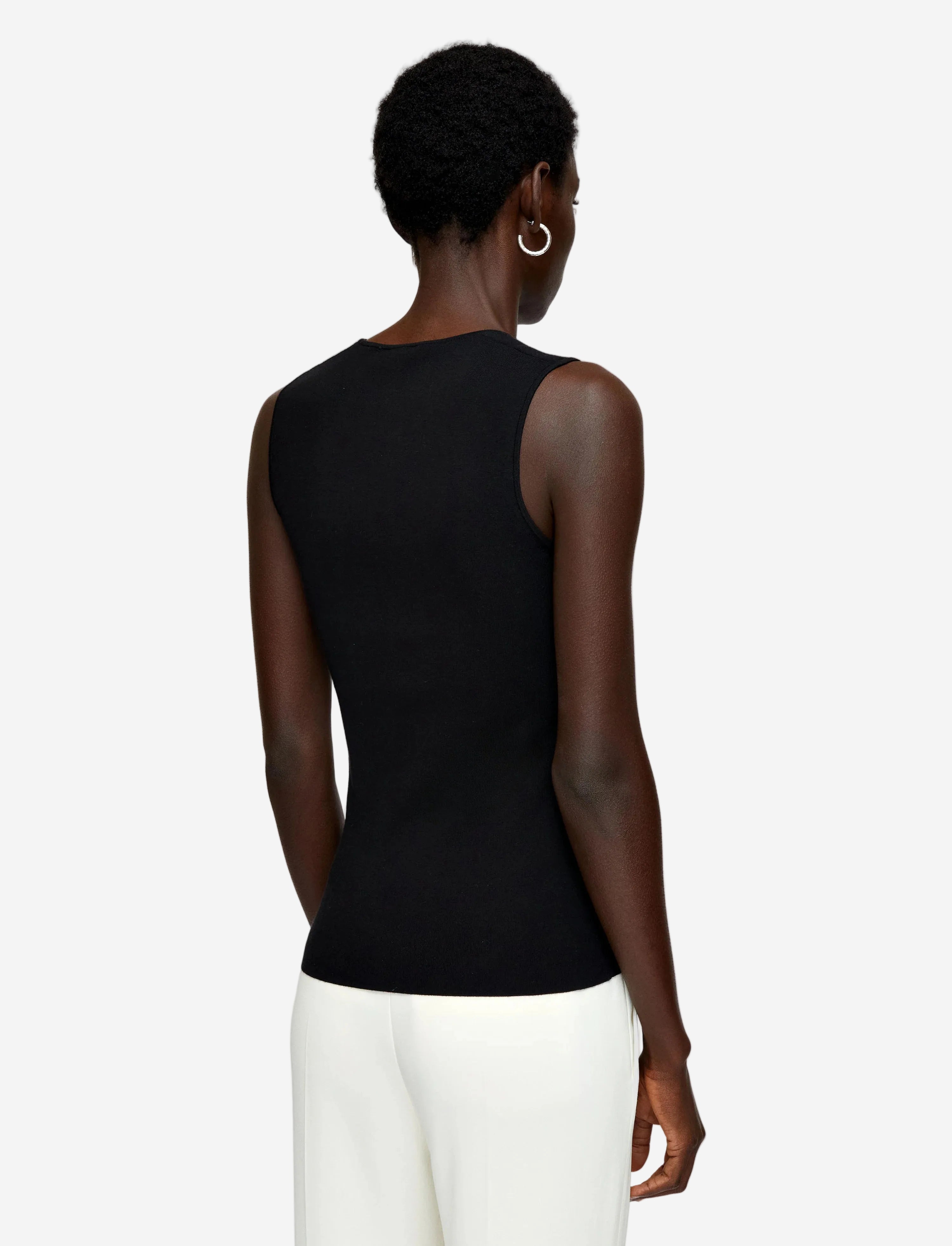 Person wearing a black sleeveless top with sheer mesh panels on a light gray background