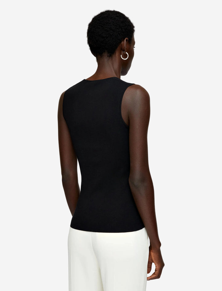 Person wearing a black sleeveless top with sheer mesh panels on a light gray background
