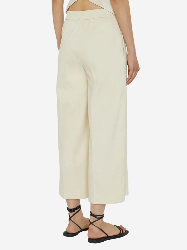 Person wearing light-colored wide-leg pants on a white background