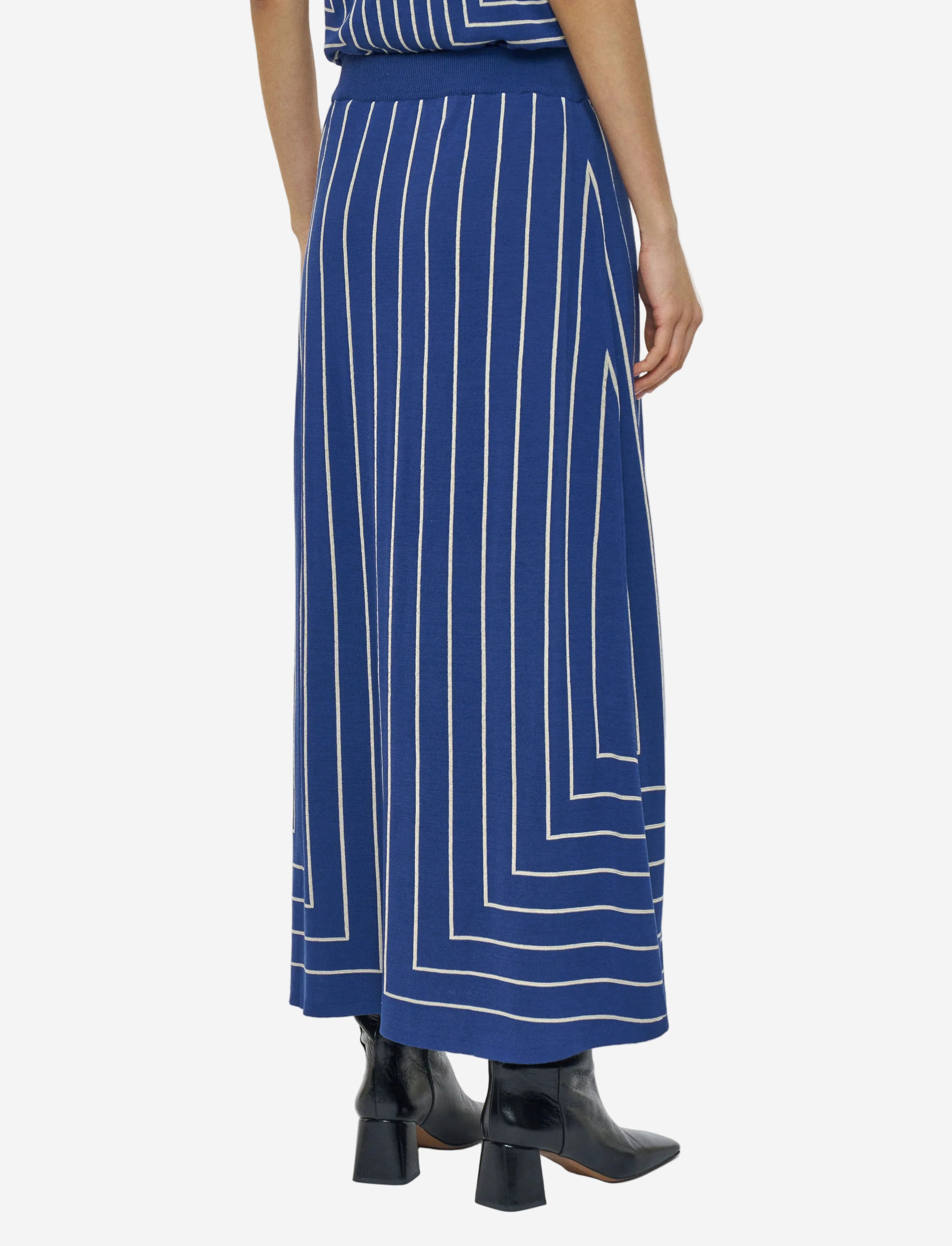 Blue skirt with white geometric pattern worn by a person on a light gray background