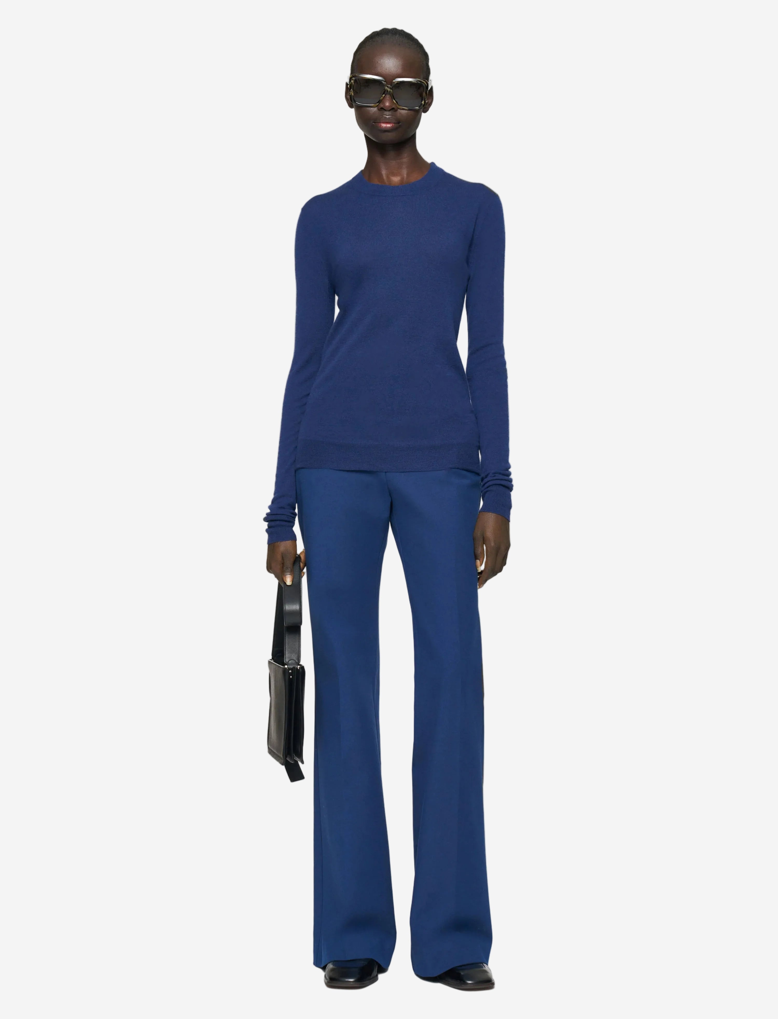 Person wearing a blue outfit with sunglasses on a white background