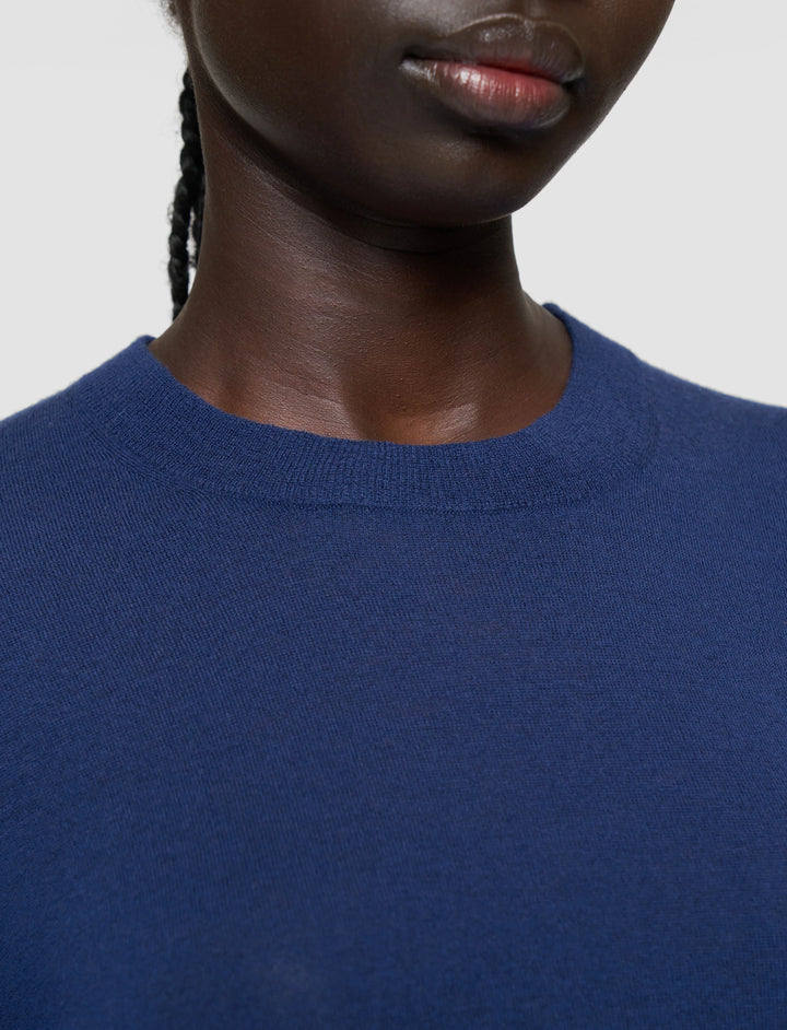 Person wearing a blue sweater against a plain background