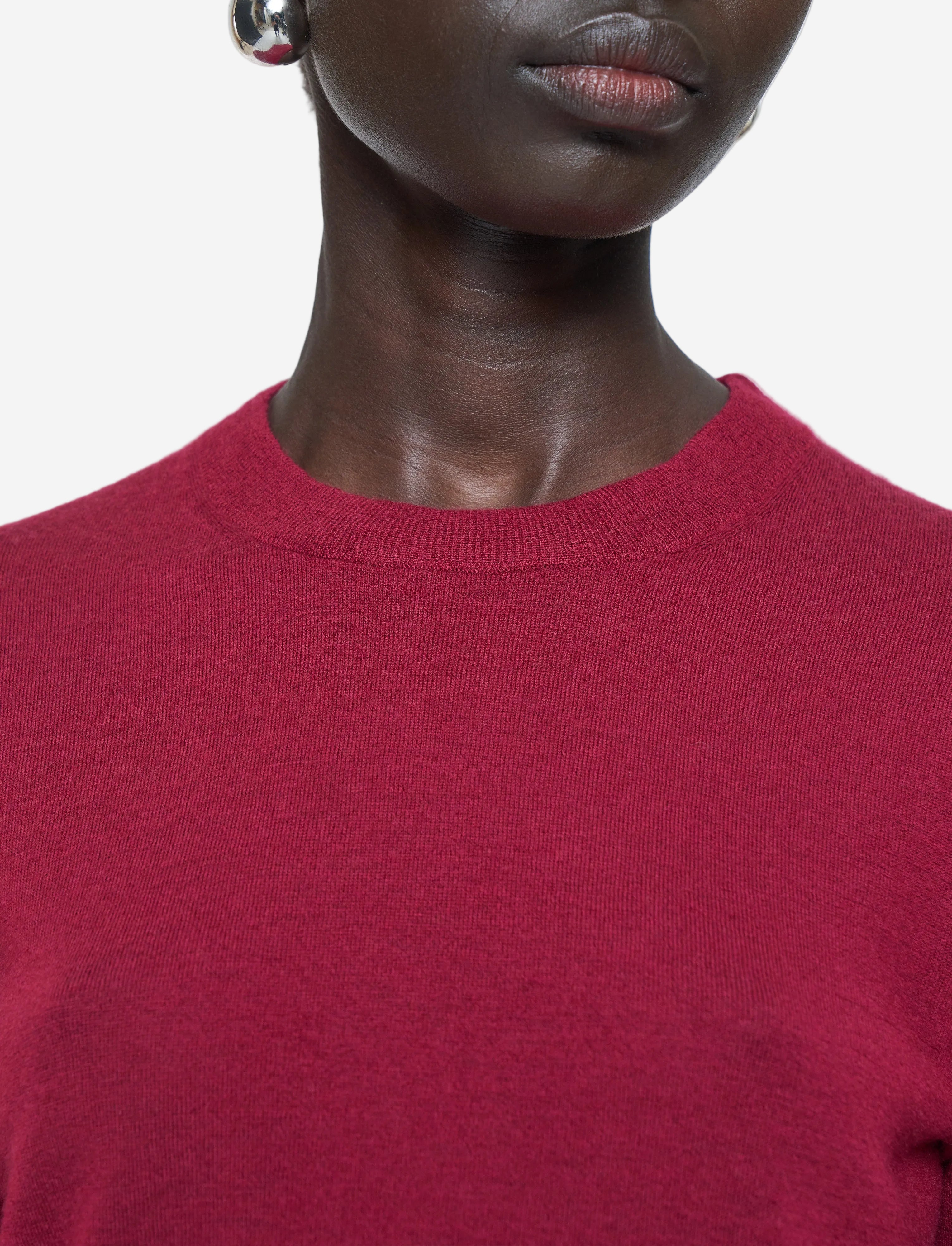 Person wearing a red sweater against a white background