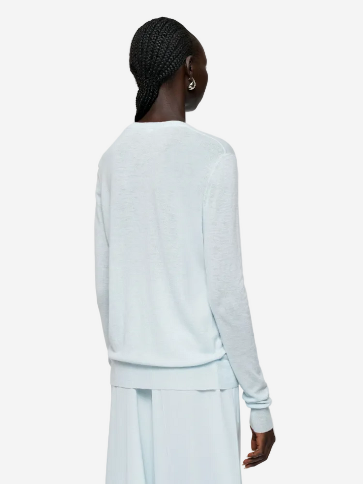 Person wearing a light blue long-sleeve top and pants on a white background