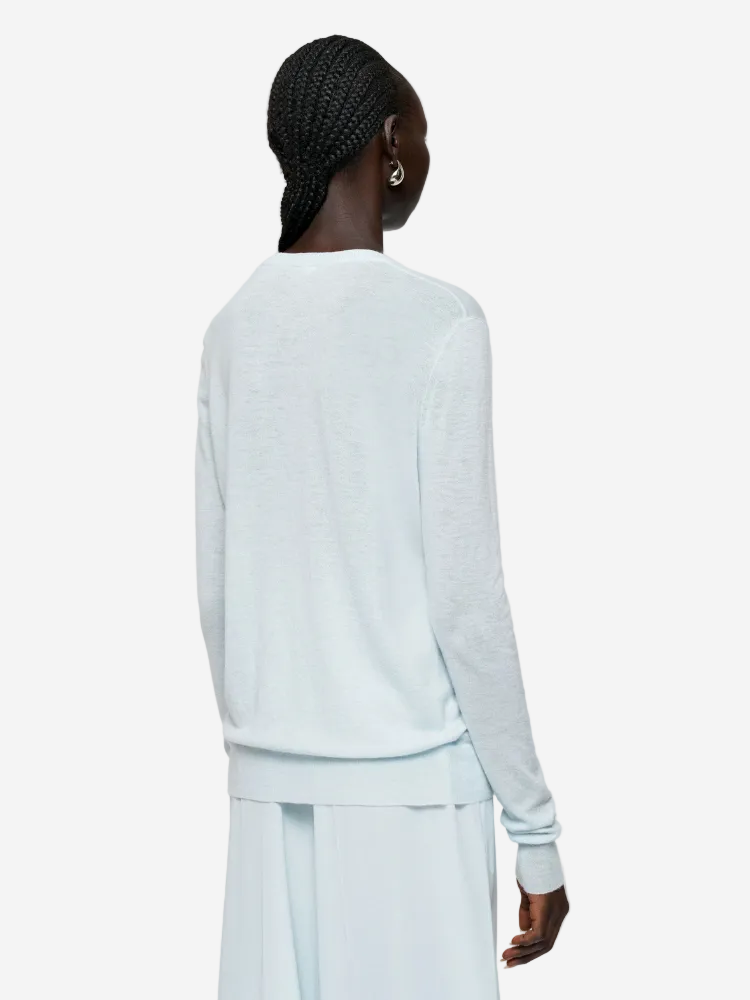 Person wearing a light blue long-sleeve top and pants on a white background