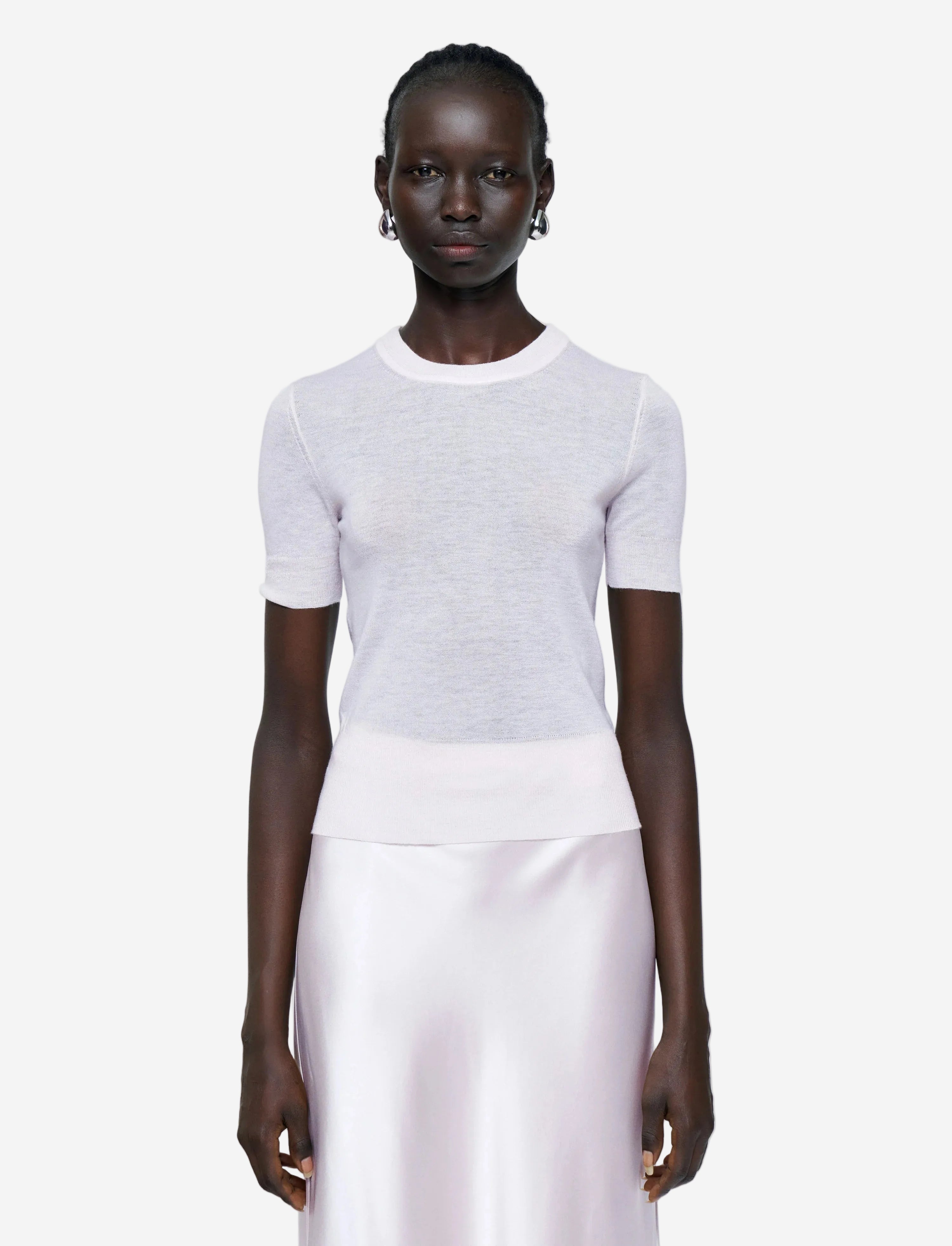 Person wearing a white short-sleeve top and light pink pants on a plain background
