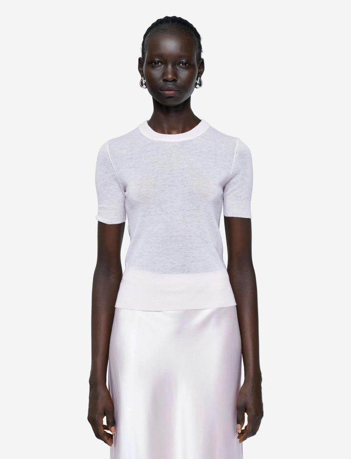 Person wearing a white short-sleeve top and light pink pants on a plain background