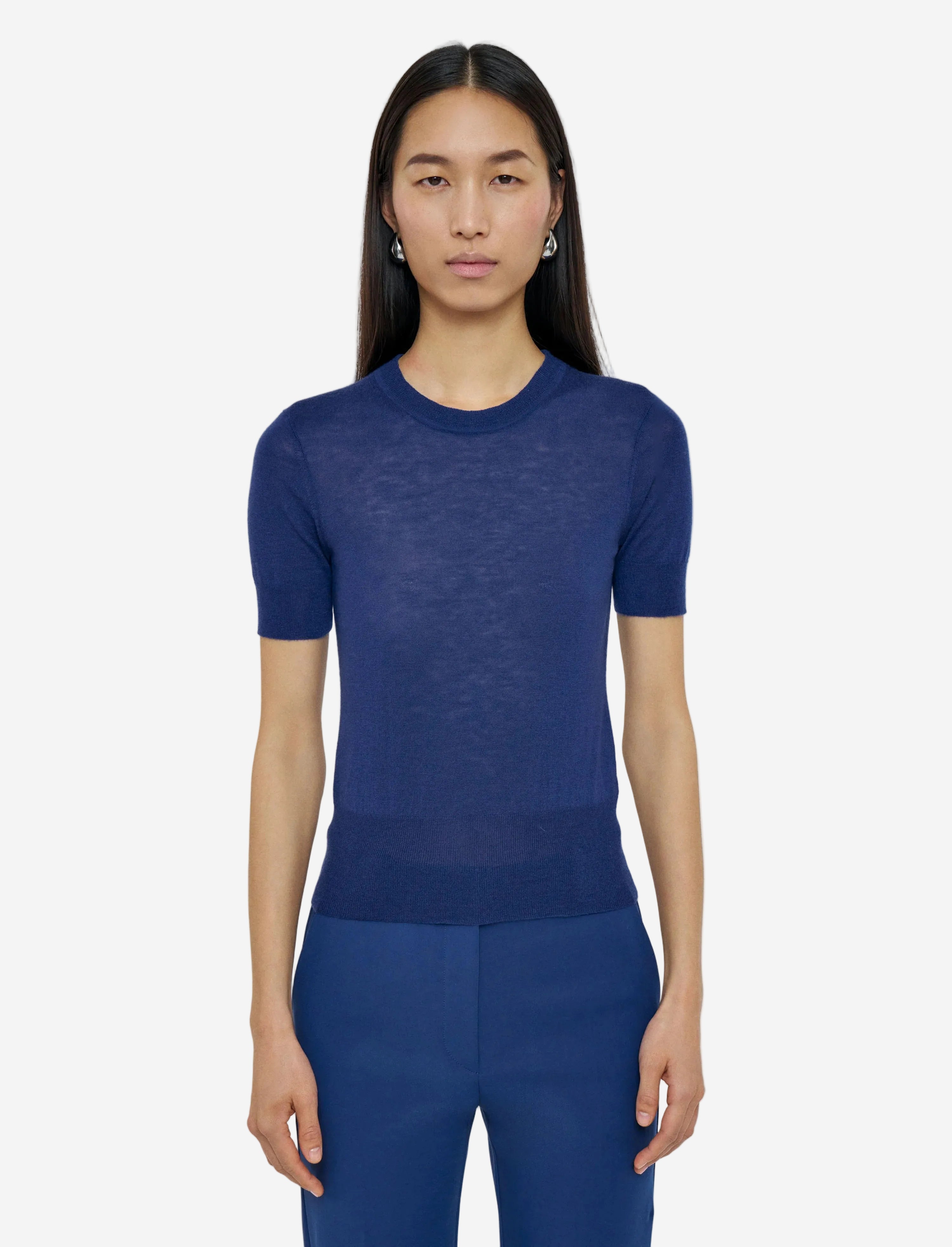 Woman wearing a blue knit top and pants on a light gray background
