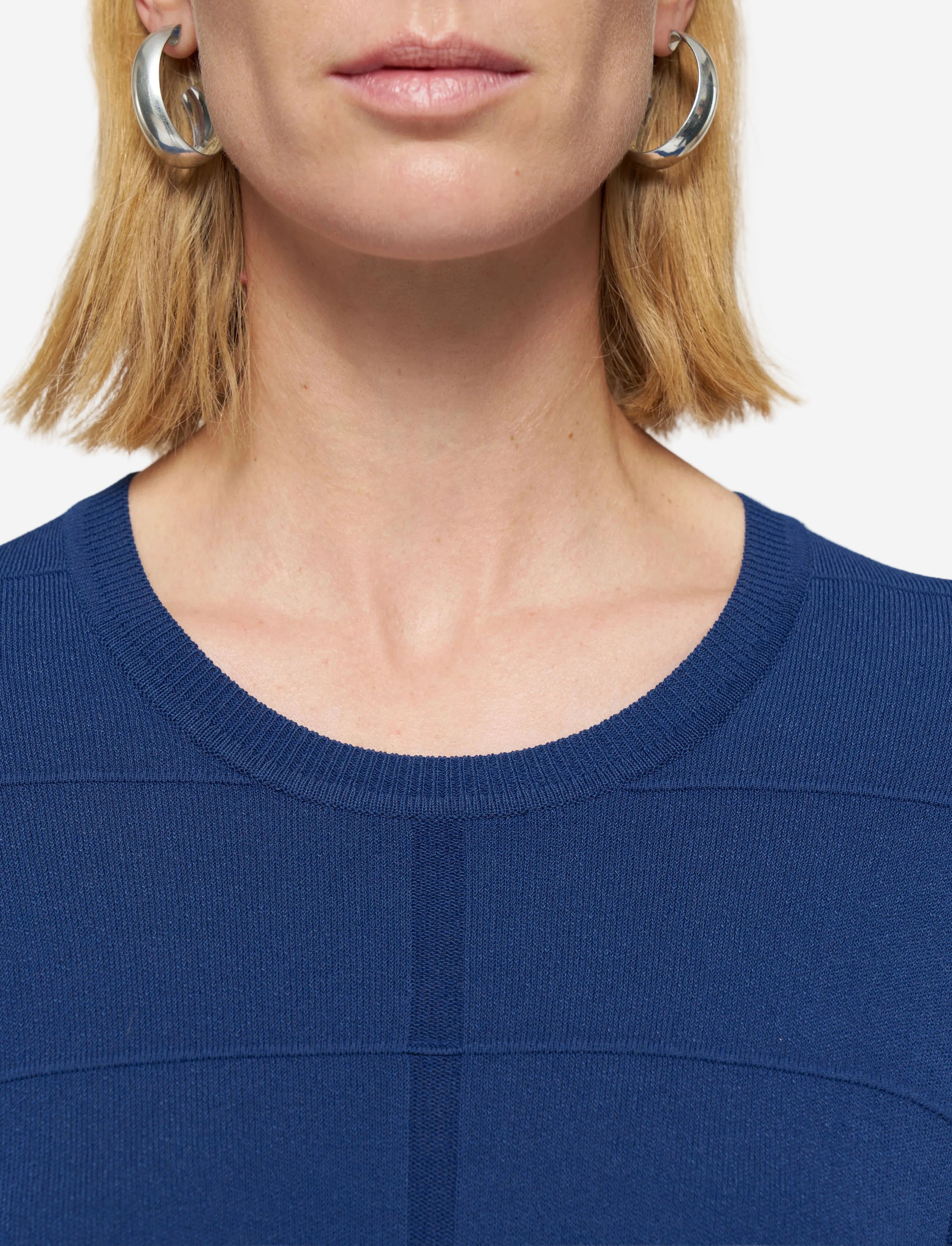 Close-up of a person wearing a blue top with a plain background