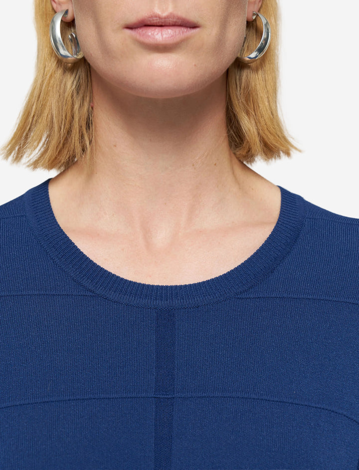Close-up of a person wearing a blue top with a plain background