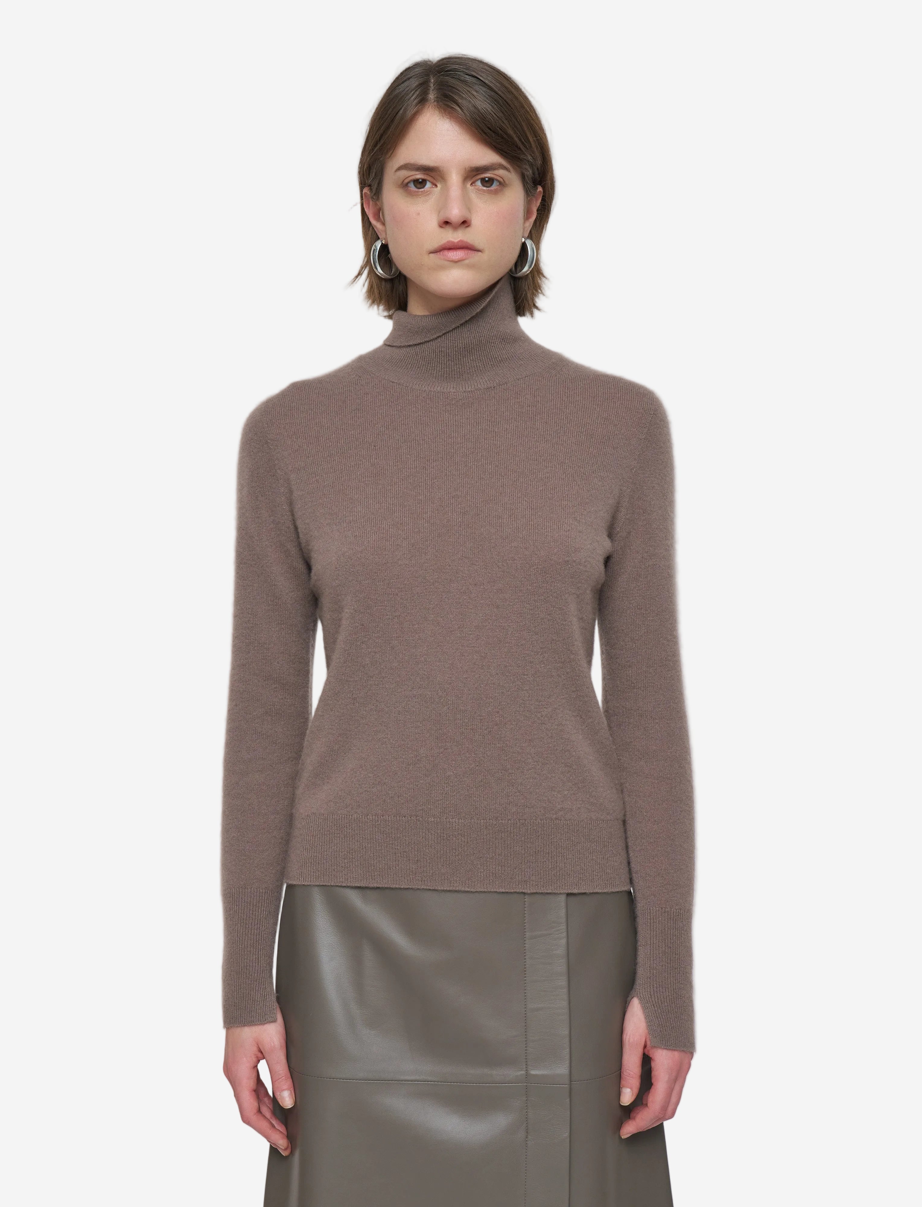 Woman wearing a brown turtleneck sweater and green skirt on a white background
