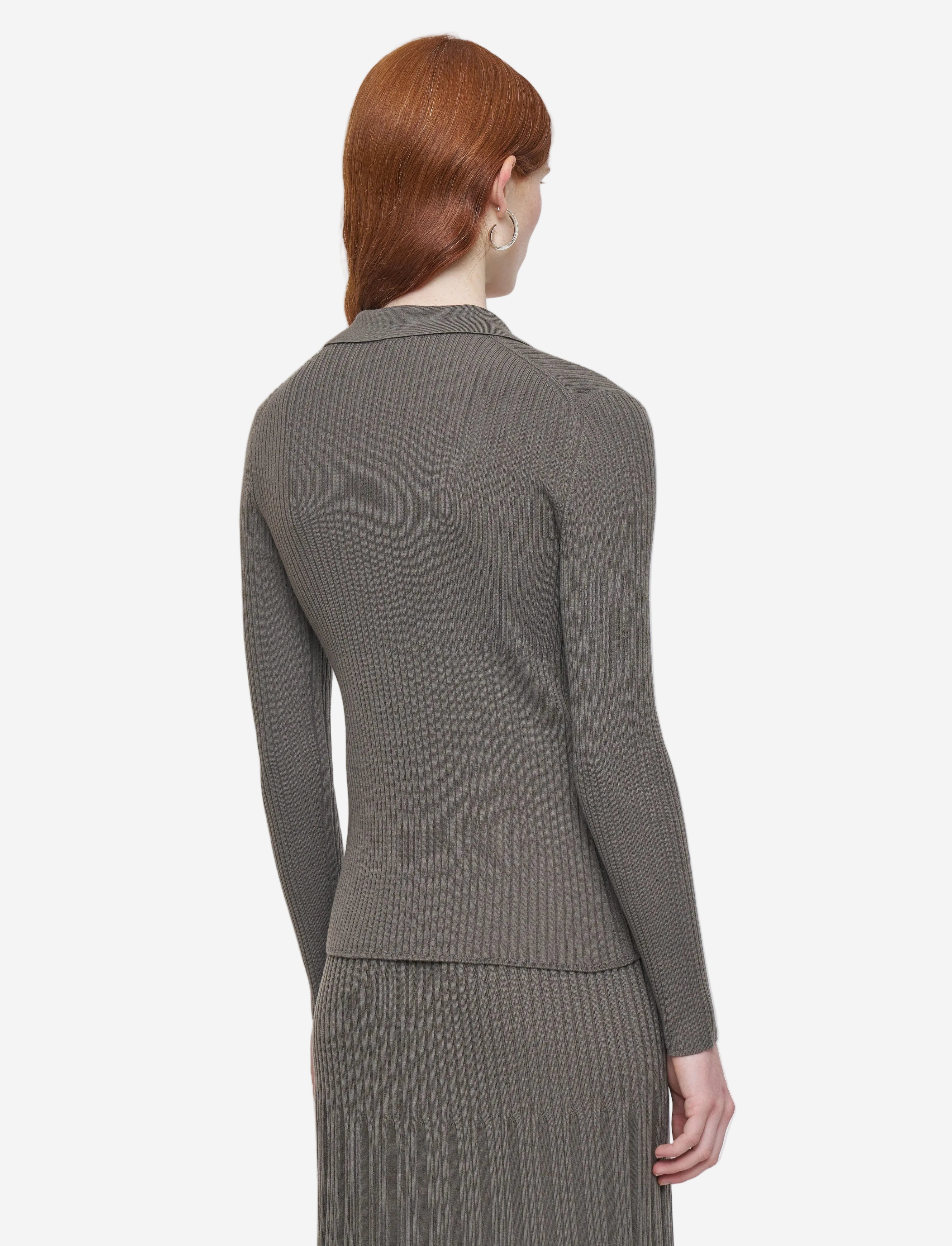 Woman wearing a gray ribbed sweater and skirt set on a light gray background