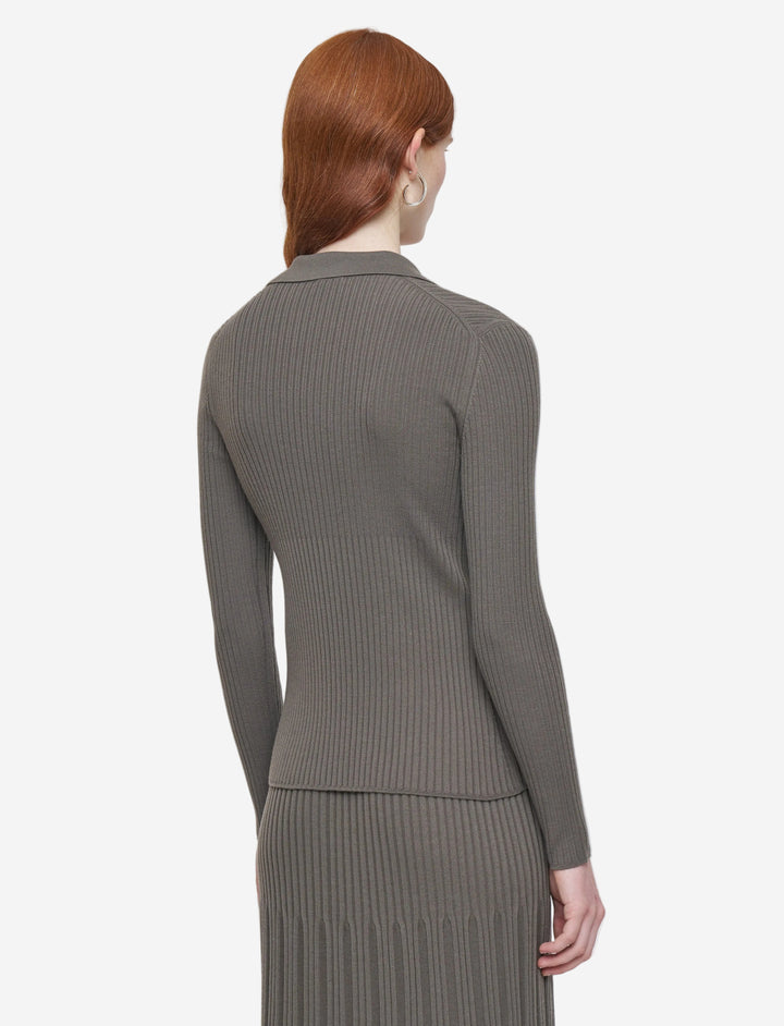 Woman wearing a gray ribbed sweater and skirt set on a light gray background