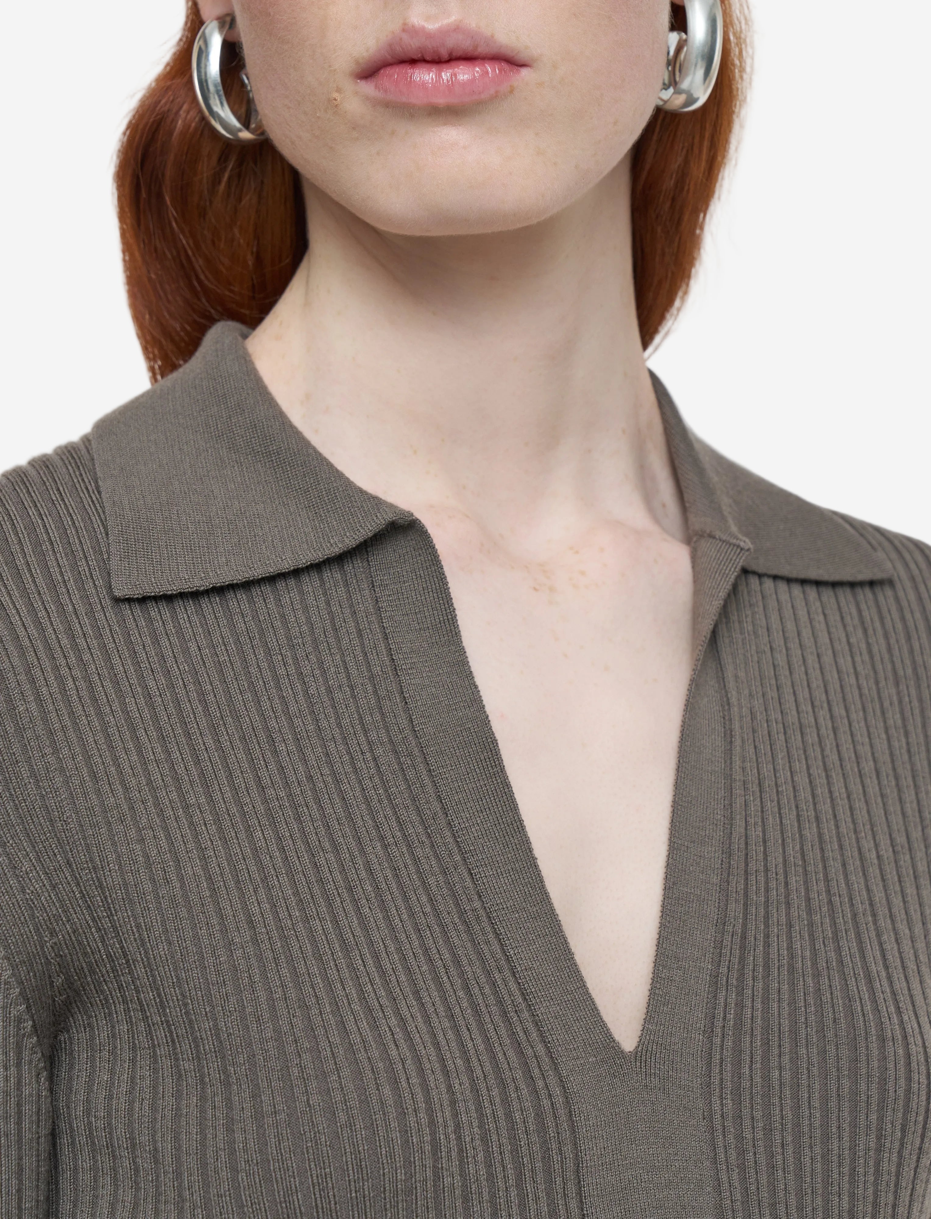Close-up of a person wearing a ribbed brown sweater with a deep neckline.