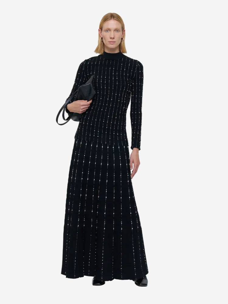 Woman wearing a black dress with white patterns on a white background