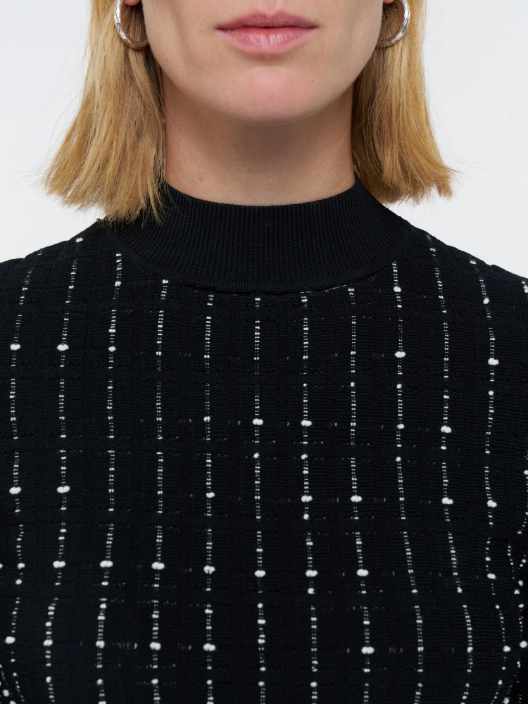 Close-up of a person wearing a black sweater with white pattern against a white background