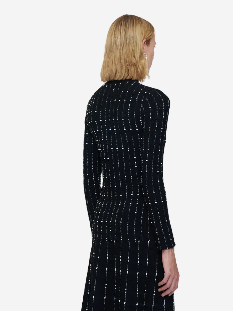 Woman wearing a black dress with white patterns from the back on a white background
