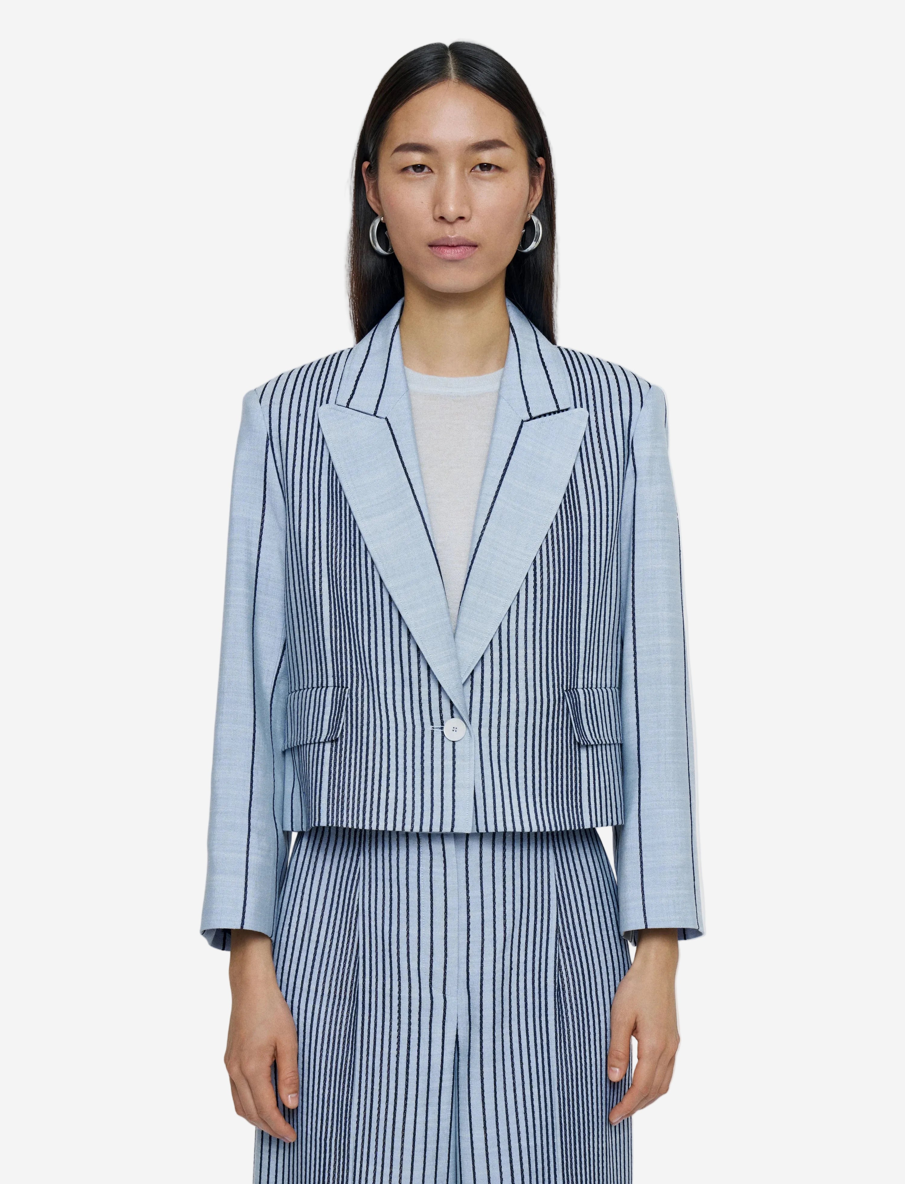 Woman wearing a blue and white striped suit on a plain background