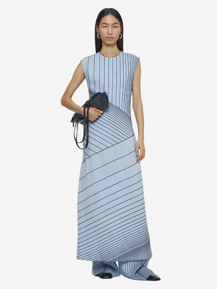 Woman wearing a blue and white striped dress holding a black handbag on a white background