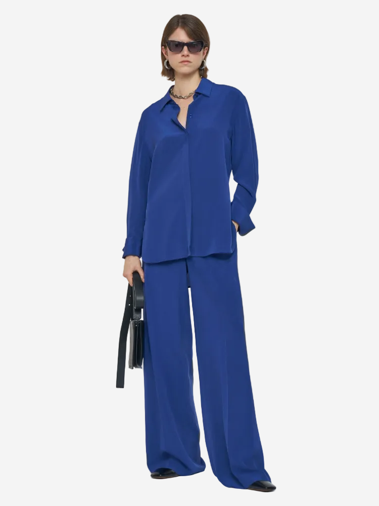 Person wearing a blue outfit with sunglasses on a white background