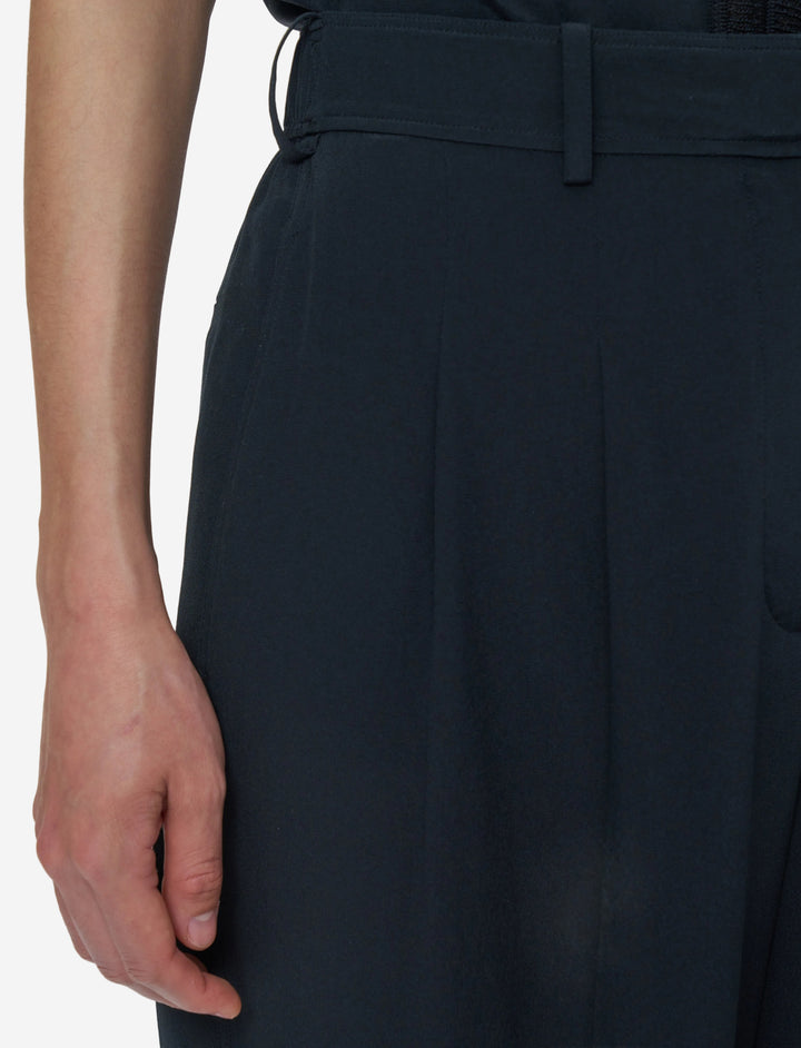 Close-up of a person wearing black pants with a belt on a white background