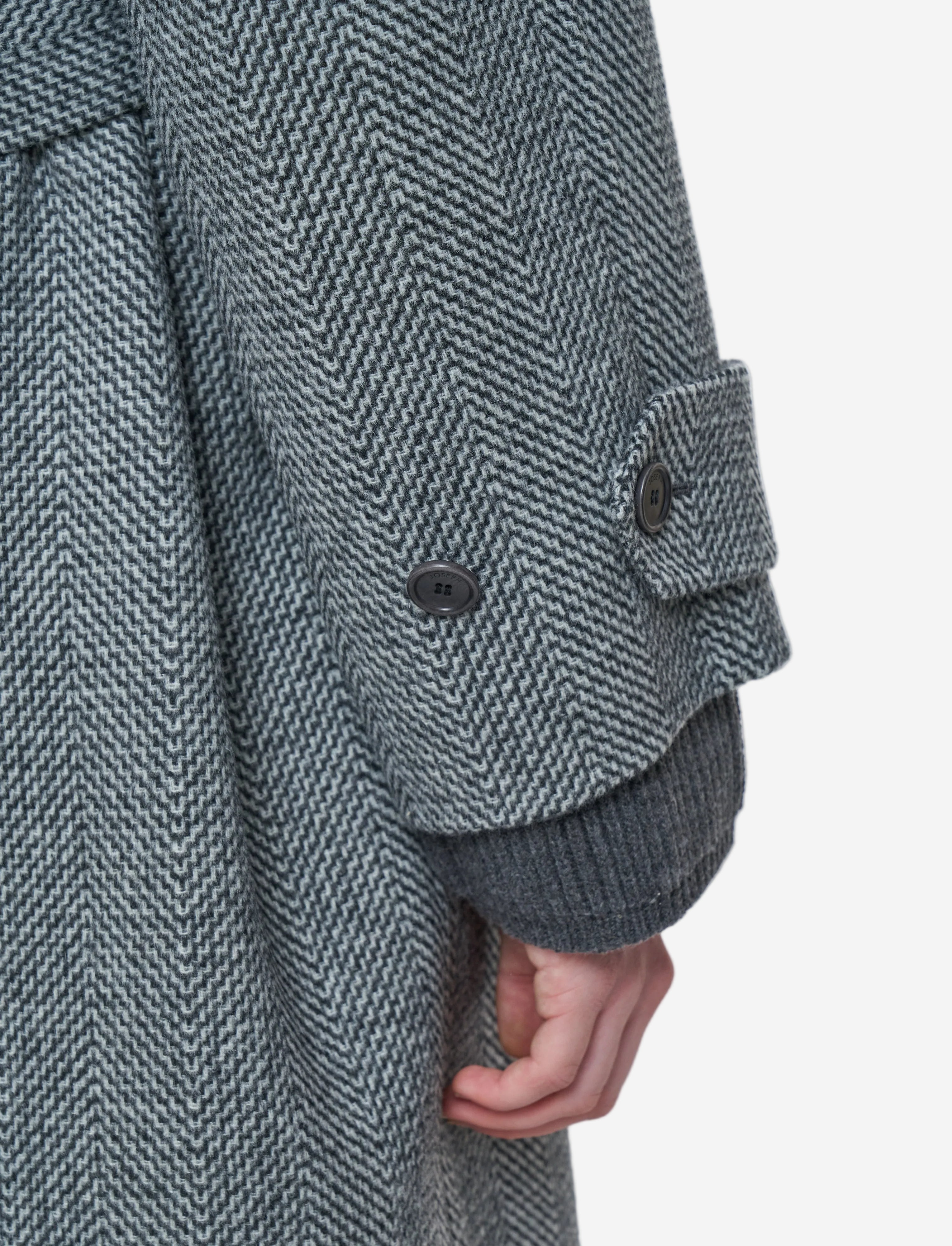 Close-up of a textured gray coat with a white background