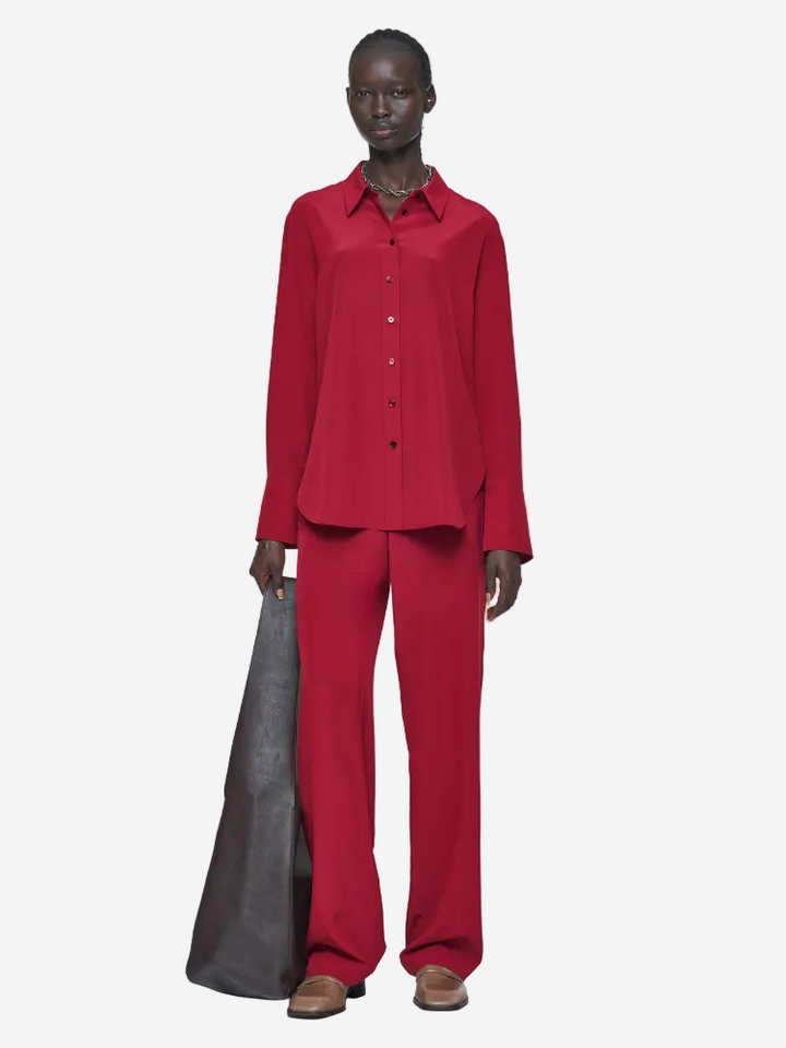 Person wearing a red outfit holding a gray bag on a white background
