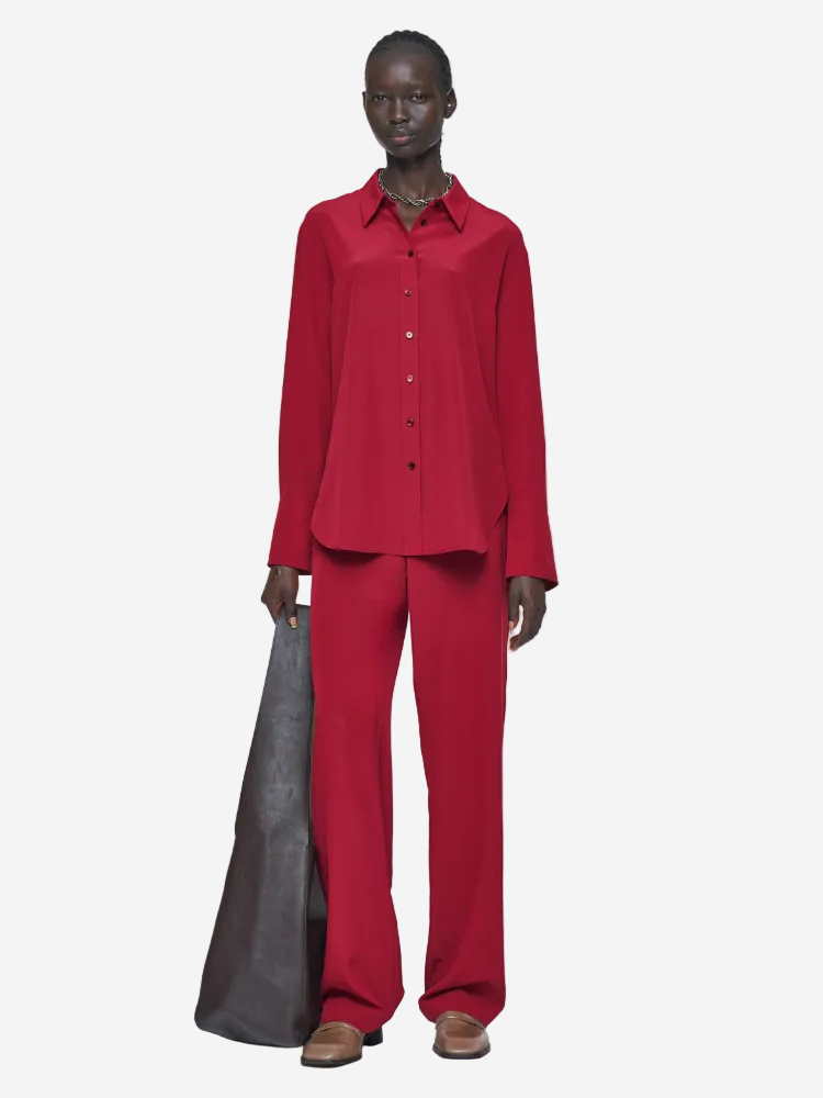 Person wearing a red outfit holding a gray bag on a white background