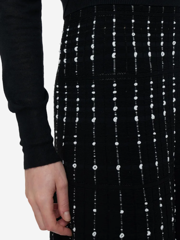 Black skirt with white dot pattern worn by a person on a white background